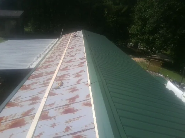 Old rusted panels beside newly installed green metal roofing — Wind Damage Roof Repair by Roofing Brothers in Mitchells