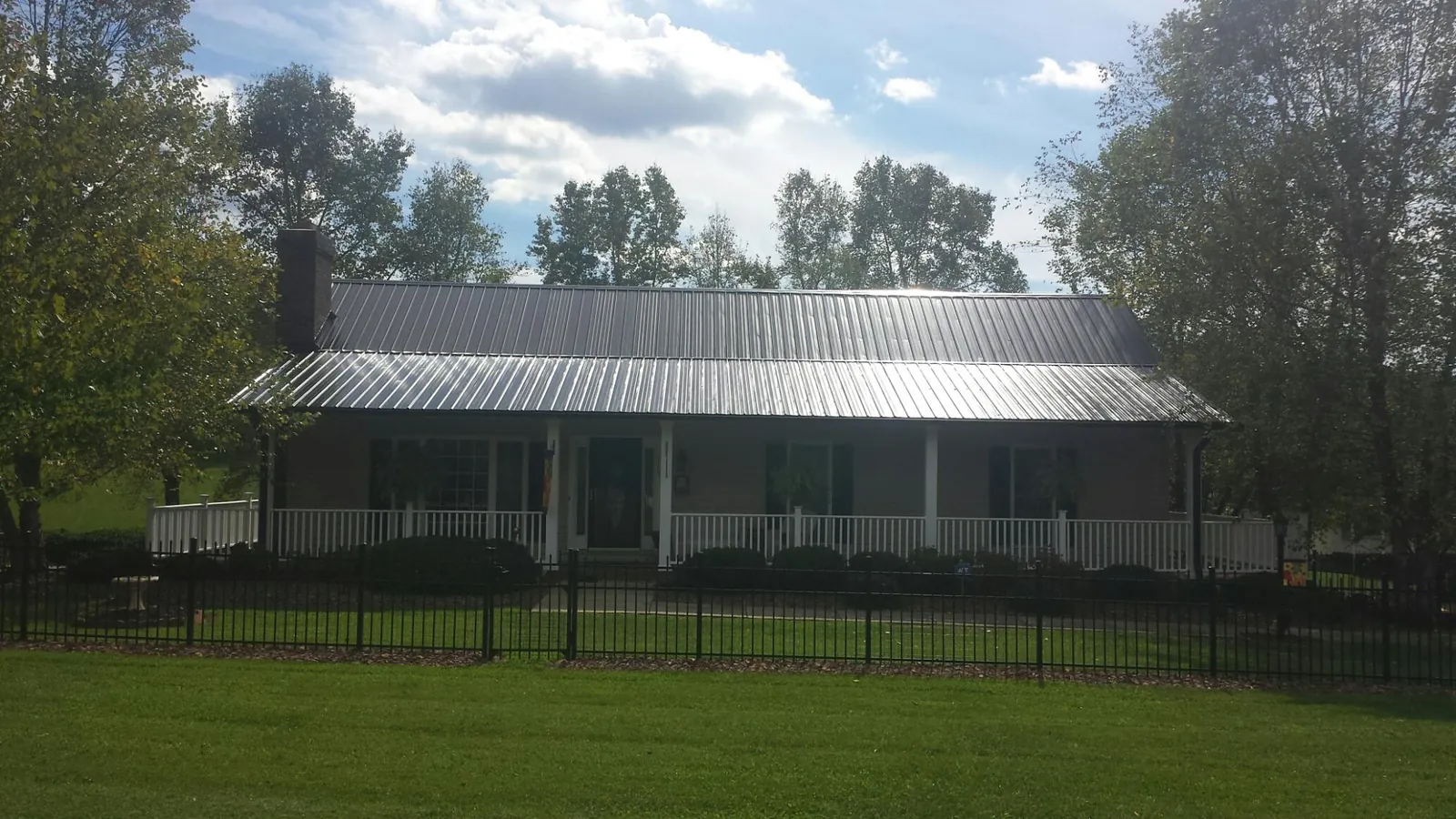 Gray metal roof on a brick ranch with a full width front porch — Gutter Guard Installation work by our crew in Mitchells